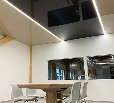 Modernes Büro mit einer schwarzen Teildeckenheizung und zusätlicher Beleuchtung