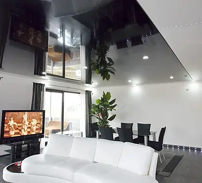 Ein modernes Wohnimmer mit einer schwarzen, beleutchteten Deckenheizung, die den halben Raum bedeckt.